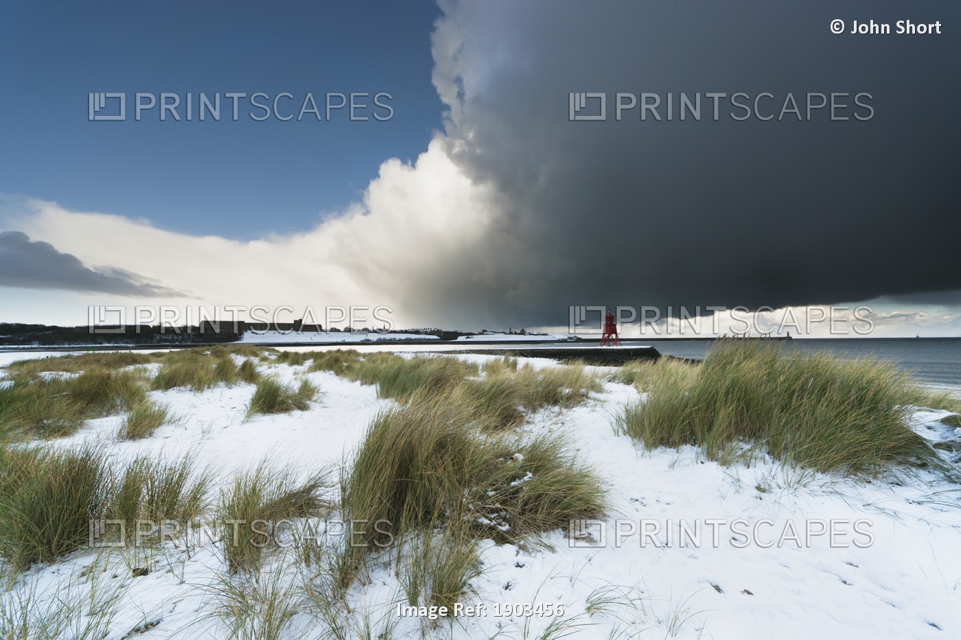 Dark Clouds And Blue Sky Over A Red Lighthouse Along The Coast In The Winter; ...