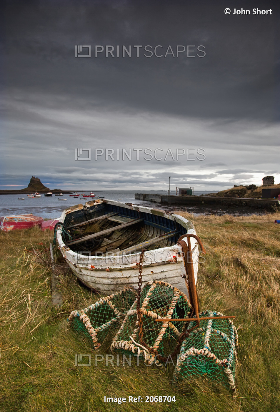 A Weathered Boat And Fishing Equipment Sitting On The Shore With Lindisfarne ...