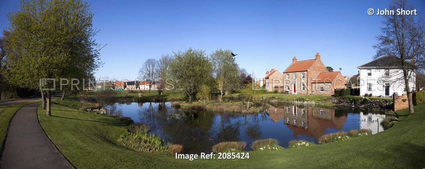 Houses Reflected In A Tranquil Pond; East Witton Yorkshire England