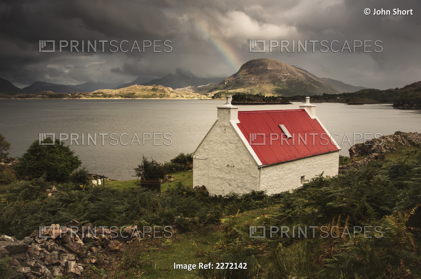 A Cottage With A Red Roof On The Water's Edge With A Rainbow In The Distance; ...