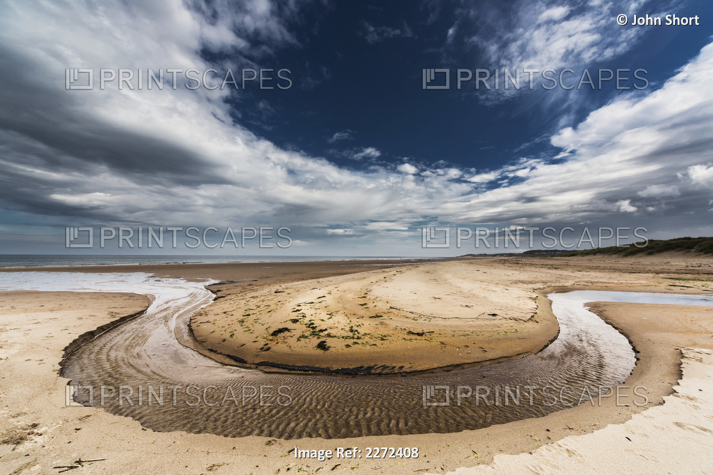 A stream formed in a circular shape in the sand along the coast;Druridge bay ...