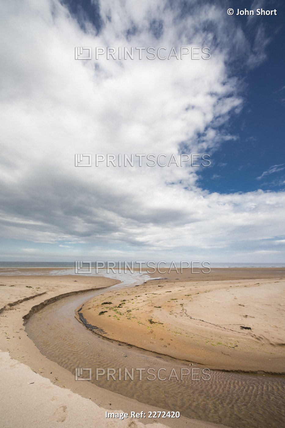 A stream formed in a circular shape in the sand along the coast; Druridge bay ...