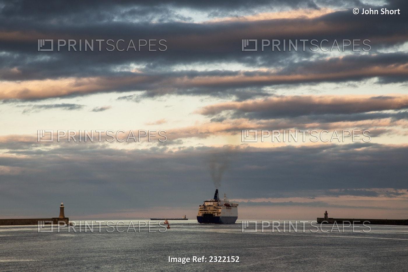 UK, England, Tyne and Wear, South Shields, Ship pulling into port at sunset