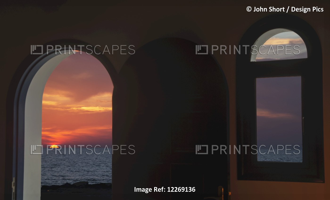 View Of A Colourful, Dramatic Sunset Over The Ocean Through An Arched Doorway; ...
