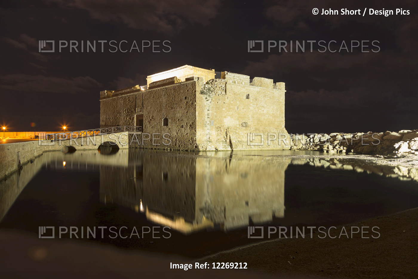 An Old Ruined Medieval Castle Reflected In Tranquil Water At Nighttime; Paphos, ...