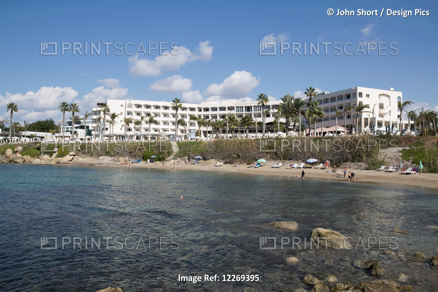 A Hotel And Palm Trees And People On The Beach; Paphos, Cyprus