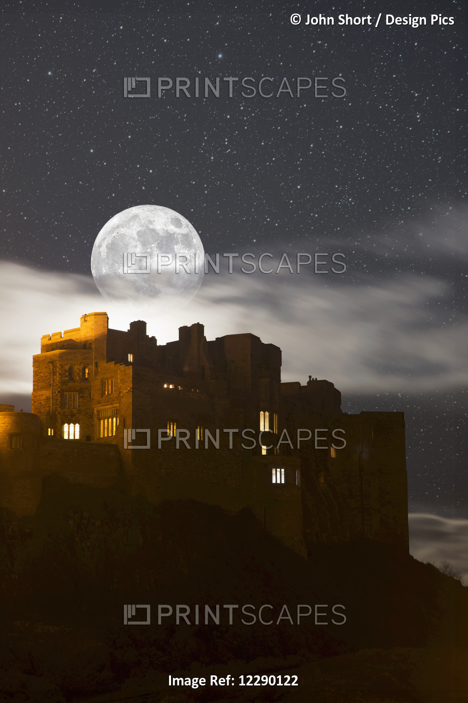 Full Moon Glowing In A Starry Sky Over Illuminated Buildings; Bamburgh, ...