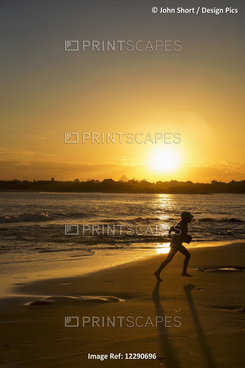 Silhouette Of A Child Running On A Beach At Sunset; Caloundra, Queensland, ...