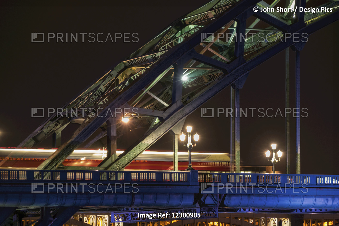 Close Up Of The Illuminated Arch Of A Bridge And Lamp Posts At Nighttime