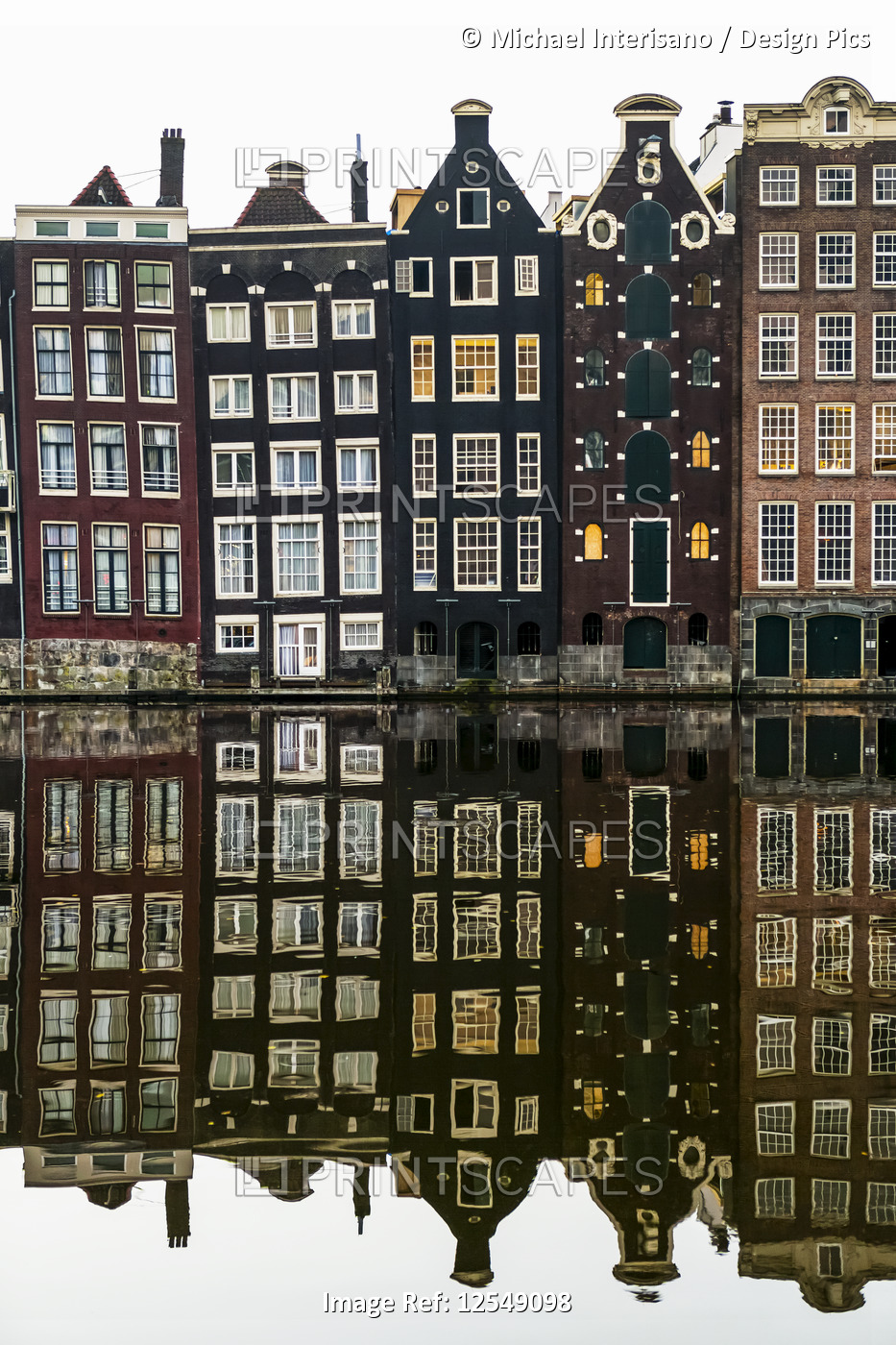 Building facades with a mirror image reflecting in a canal; Amsterdam, ...