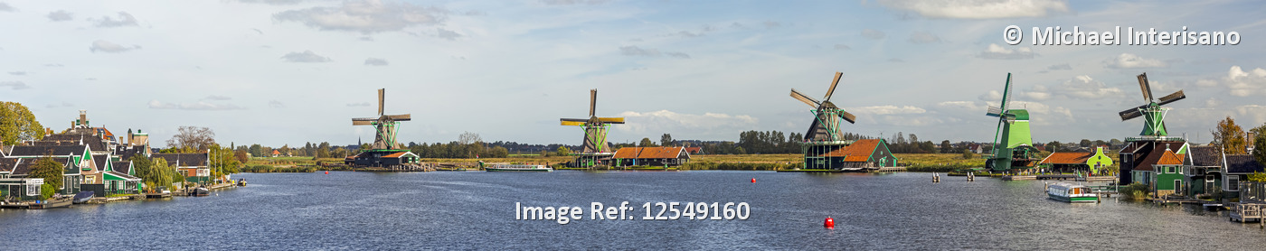 Panorama of historical wooden windmills along a riverbank with blue sky and ...