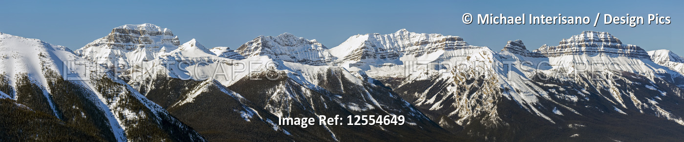 Panorama of snow-covered mountain range and blue sky; Banff, Alberta, Canada