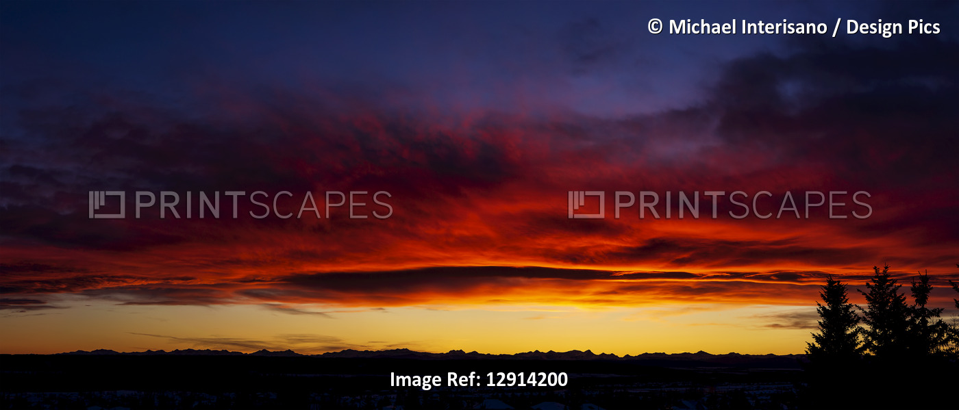Dramatic colourful sky/clouds at sunset with silhouette trees and mountain ...